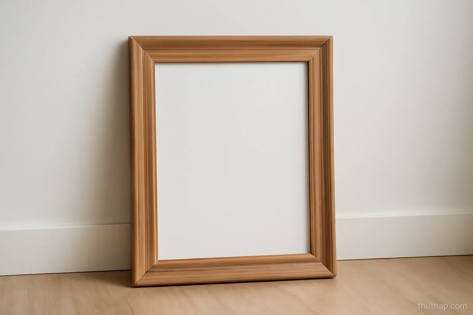 a well made empty wooden picture frame leaning against a plain white interior wall