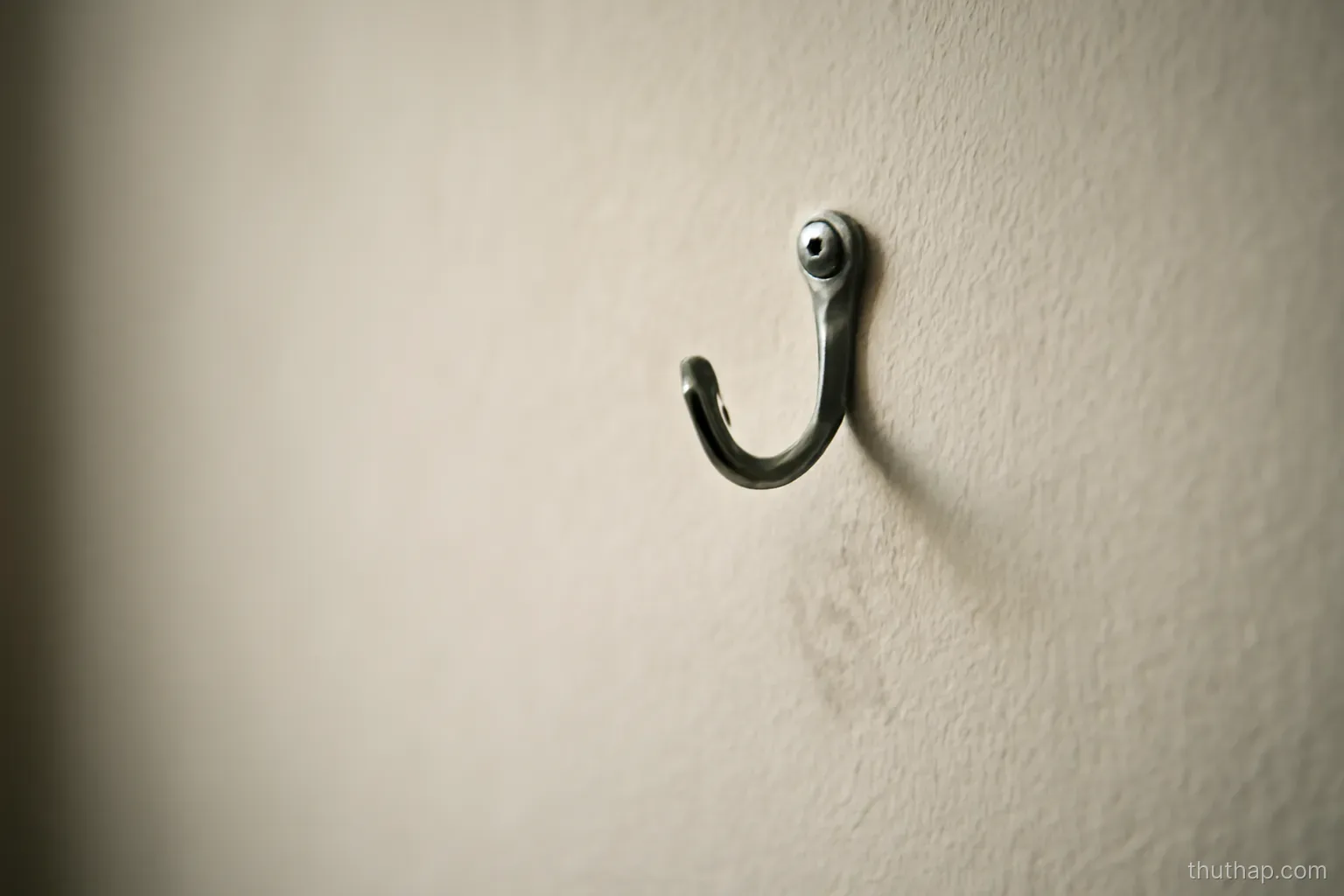 an empty hook on a bare wall with a faint mark where something used to hang